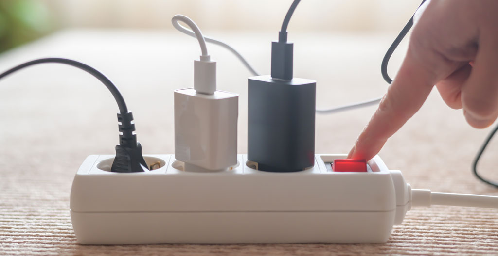 Multiprise avec interrupteurs individuels contrôlant box internet, décodeur et petits appareils sur un bureau blanc
